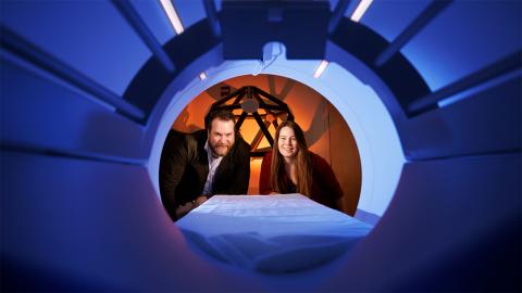 Doug Schultz (left) and Heather Bouchard peer into the chamber of an MRI machine at the Center for Brain, Biology and Behavior, located within Memorial Stadium.